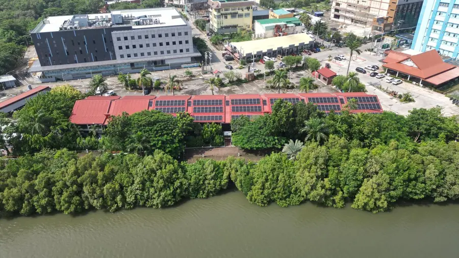 Aerial view of the red-roofed Riverside Iloilo buildings on the bank of the Iloilo River, mangroves along the water