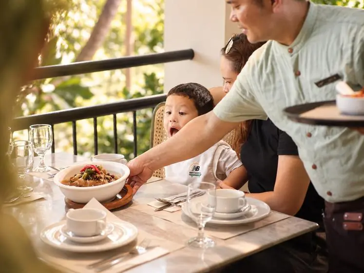 A server bringing a bowl to a boy and his mother