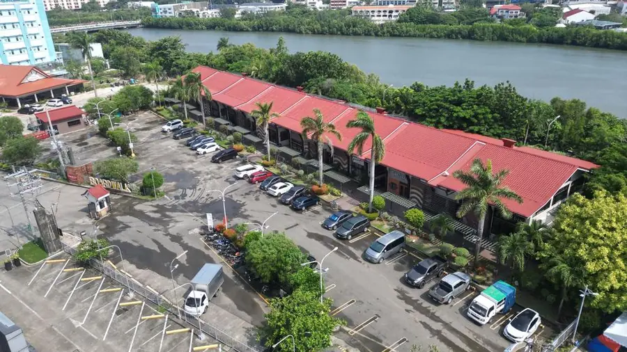 Aerial view of the red-roofed Riverside Iloilo buildings, palms and parking beside the river